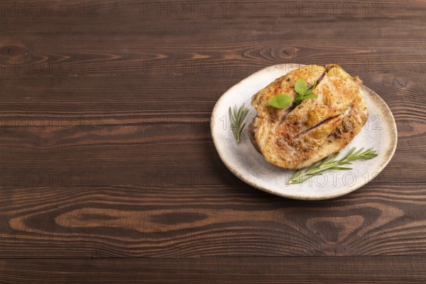 Fried Turkey Thigh with spices and rosemary on plate on brown wooden background. side view, copy space