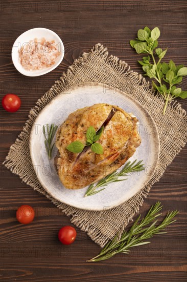 Fried Turkey Thigh with spices and rosemary on plate on brown wooden background and linen textile. top view, flat lay, close up