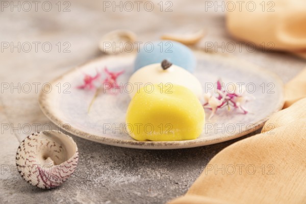 Japanese Mochi Cakes on brown concrete background and orange textile, side view, close up, selective focus