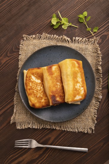 Fried crispy pancakes with meat and cheese on brown wooden background and linen textile. top view, flat lay, close up