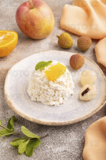 White ?ottage cheese, Curd, with orange and lychee on brown concrete background and orange textile, side view, close up