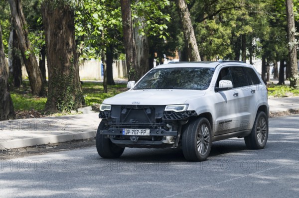White SUV with damaged front on a tree-lined road, Georgia