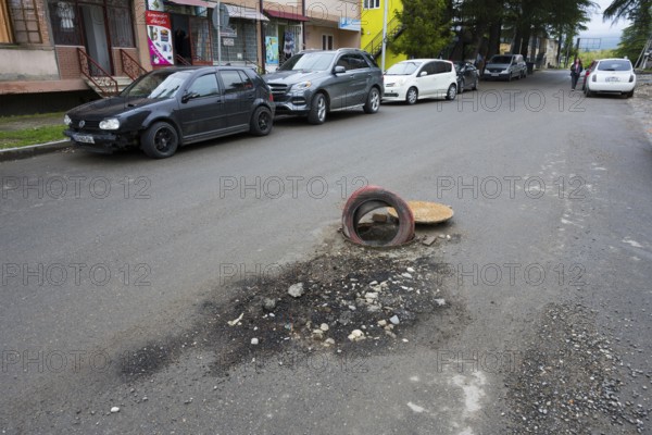 Street scene with cars along the sidewalk and a tire marking a pothole, Martvili, Mingrelia-Upper Svaneti region, Georgia
