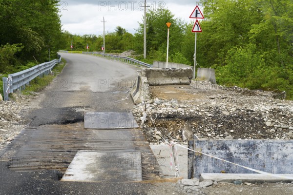 Partially closed road with signs and debris surrounded by green vegetation, bridge over the Techuri River, Nokalakevi, Mingrelia region and Upper Svaneti, Georgia