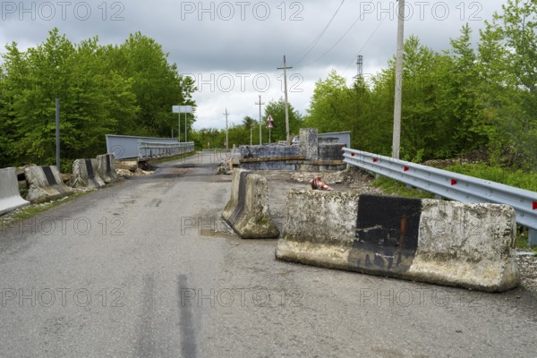 Road with concrete barriers and bridge in a rural area under cloudy sky, bridge over the Techuri River, Nokalakevi, Mingrelia region and Upper Svaneti, Georgia