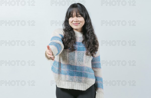 Attractive Asian girl greets you with open hand isolated. Cheerful woman extending her hand to the camera welcoming you
