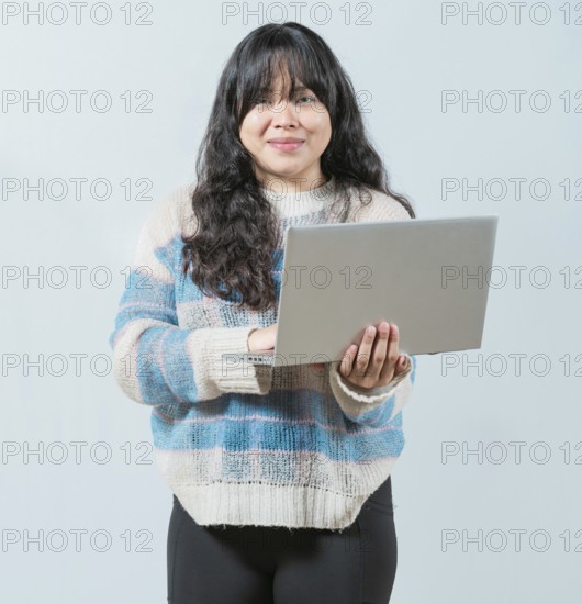 Beautiful asian girl using laptop and looking at camera isolated. Smiling asian woman using notebook and looking at camera