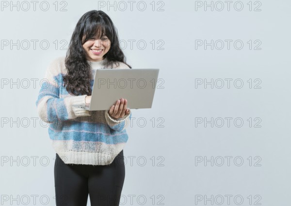 Smiling asian girl holding and looking on laptop screen isolated. Portrait of beautiful asian woman using and looking laptop