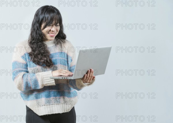 Happy asian girl looking on laptop screen isolated. Portrait of beautiful asian woman using laptopand looking screen