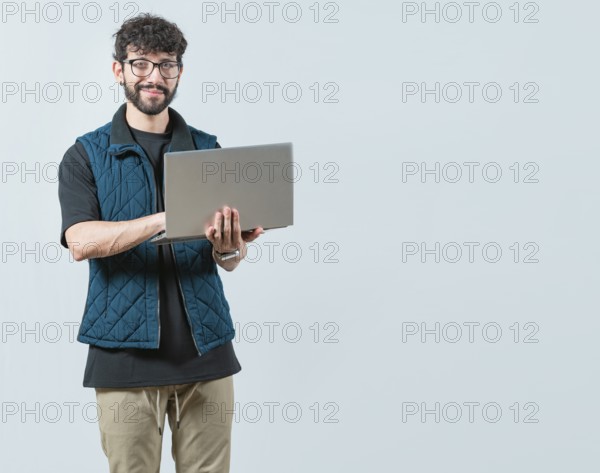 Smiling Bearded guy using laptop and looking at camera isolated. Handsome young man with glasses laptop and looking at camera