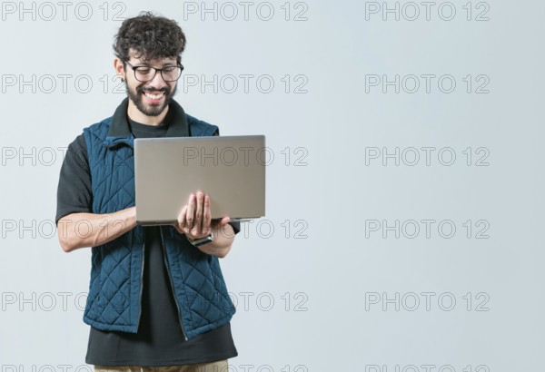 Handsome young man with glasses holding and looking on laptop screen. Portrait of Bearded guy using and looking laptop isolated