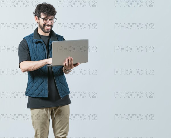 Portrait of Bearded guy using and looking laptop isolated. Handsome young man with glasses holding and looking on laptop screen
