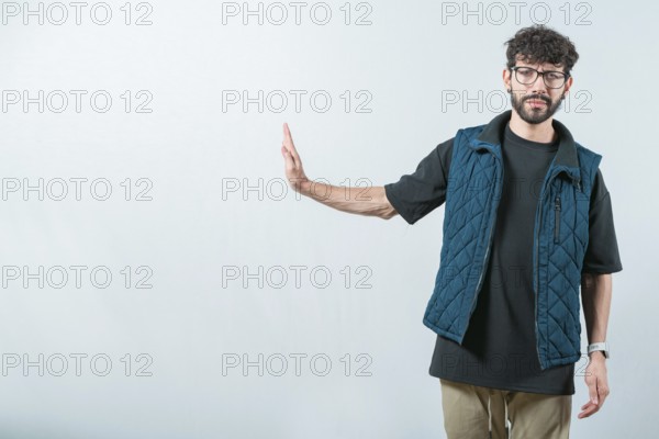 Serius guy making rejection gesture with palm of hand isolated. Displeased young man ignoring with palm hand