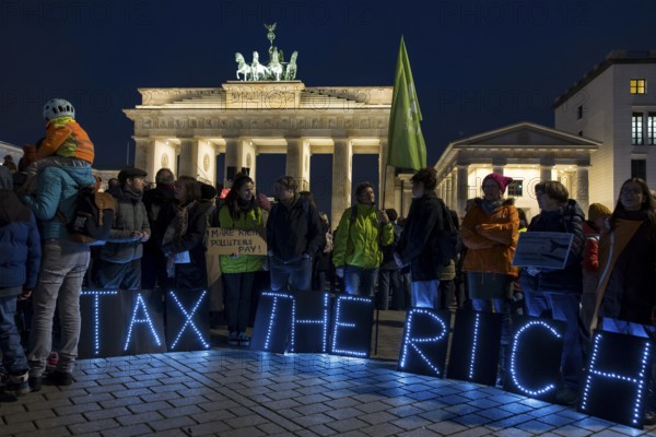 Participants set up glowing letters with the inscription Tax The Rich at the international climate demo under the slogan Fight for 1.5 at the Brandenburg Gate in Berlin on 14.11.2025. The demonstration takes place on the occasion of the COP30 World Climate Conference in Belém, Brazil, and to mark 10 years of the Paris Climate Agreement