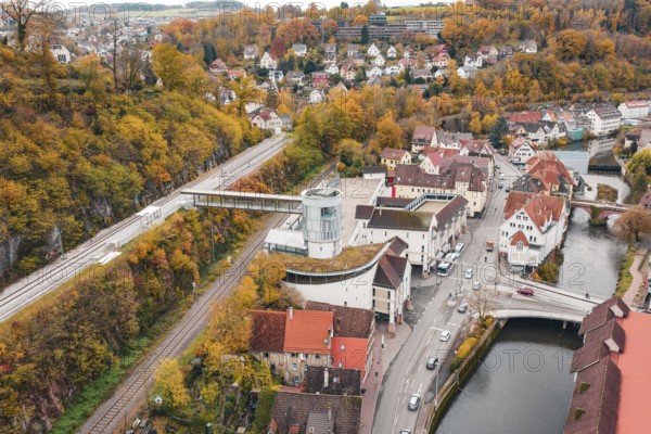 Idyllic small town in autumn colors with a river and bridge, surrounded by colorful trees. Railway station at the edge of the forest, Hermann Hessebahn, ZOB Calw, Germany