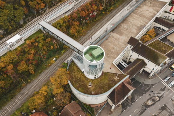 View of tower next to train tracks and parking lot, surrounded by autumn colors, Hermann Hessebahn, ZOB Calw, Germany