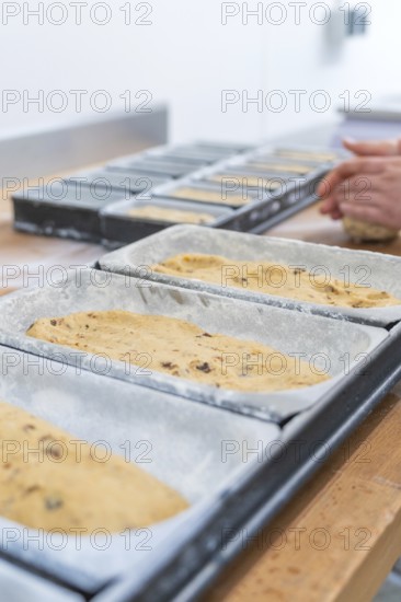 Dough in loaf pans, hands of a baker working dough in the background, Christmas baking, Haselstaller Hof, Wildberg, Germany