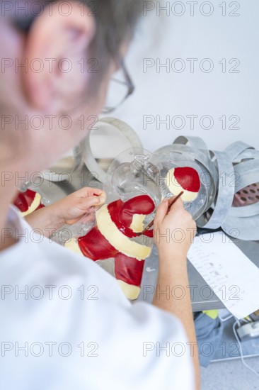 Person decorating a Santa Claus mold with red and white paint, Christmas baking, Haselstaller Hof, Wildberg, Germany