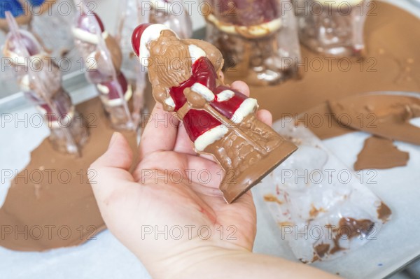One hand holds a half-finished chocolate Santa Claus on a work surface, Christmas baking, Haselstaller Hof, Wildberg, Germany