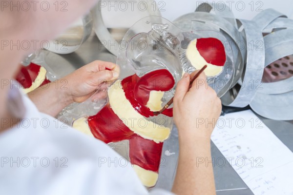 A person paints details in a chocolate Santa Claus mold, Christmas baking, Haselstaller Hof, Wildberg, Germany