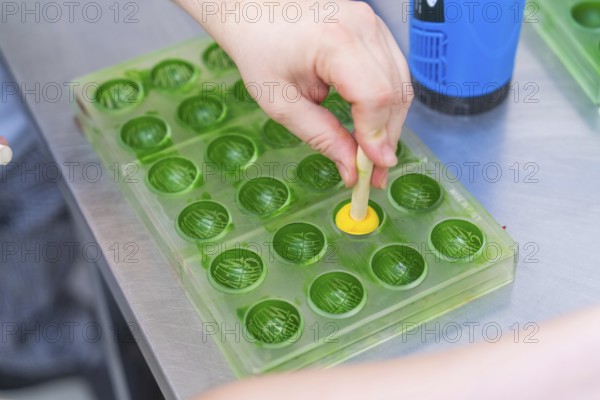 A hand forms a praline in a green chocolate mold, Christmas baking, Haselstaller Hof, Wildberg, Germany