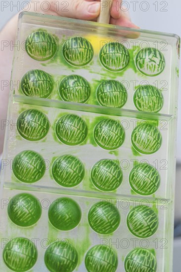 Green chocolate mold with the text 'Merry Christmas' in a chocolate workshop, Weihnachtsbacken, Haselstaller Hof, Wildberg, Germany