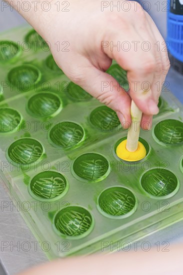 A hand shapes a yellow chocolate with a green chocolate mold, Christmas baking, Haselstaller Hof, Wildberg, Germany