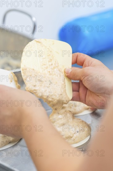 Dough is held by one hand with a silicone spatula and poured into a mold, Weihnachtsbacken, Haselstaller Hof, Wildberg, Germany