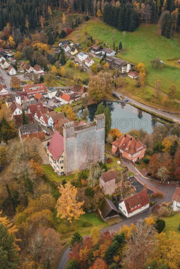 A castle next to a river in the middle of an autumn-colored village, Berneck Castle, Altentsteig, Calw district, Germany
