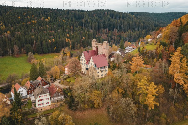 A castle and a small village nestled in an autumn forest landscape, Berneck Castle, Altentsteig, Calw district, Germany