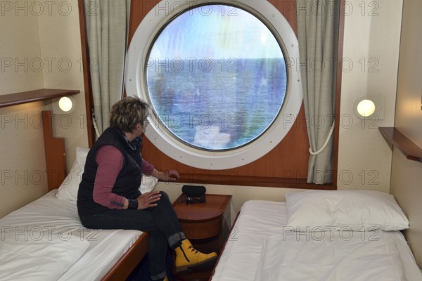 Woman looking out of her ship cabin at the sea, Baltic Sea, Color Line ferry, Schleswig-Holstein, Germany