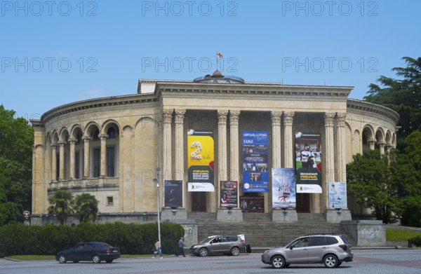 A round classical building with pillars and posters against a blue sky surrounded by green trees and cars, Lado Meskhishvili Dramatic Theatre, David Aghmashenebeli Central Square, Kutaisi, Kutaisi, Imereti Region, Georgia