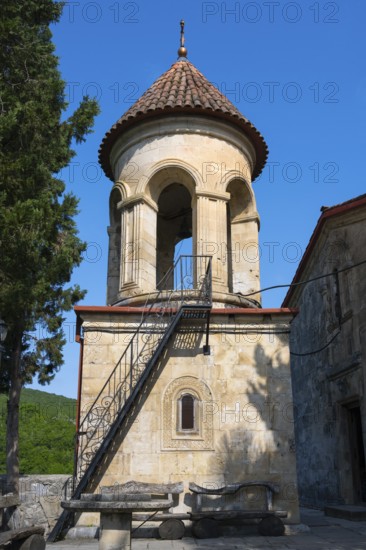 Round church tower with stone steps and red roof, immersed in quiet rural surroundings, Motsameta monastery, near Kutaisi, Imereti region, Georgia