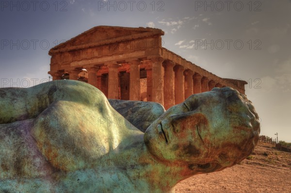 Bronze statue of fallen Icarus, Temple of Concordia, bronze statue in front of an ancient temple in an archaeological site, Valley of the Temples, Valle dei Templi, Archeological Site, UNESCO World Heritage Site, Agrigento, Sicily, Italy