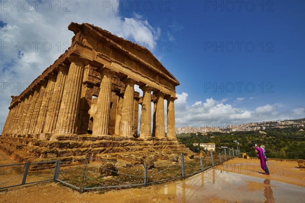 Temple of Concordia, large ancient temple with Doric columns and a person in the foreground, Valley of the Temples, Valle dei Templi, Archaeological Site, UNESCO World Heritage Site, Agrigento, Sicily, Italy