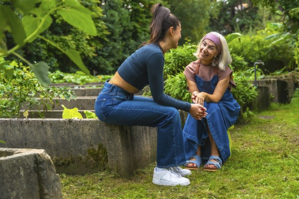 Two smiling women, a mother and daughter, enjoying a conversation outdoors, strengthening their intergenerational connection and spending quality time together in a green environment