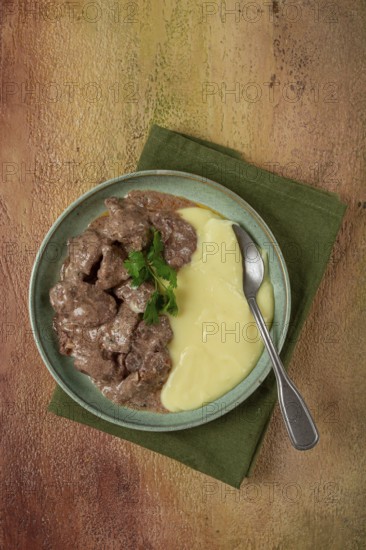 Liver beef stroganoff with mashed potatoes, table setting in green tones, homemade