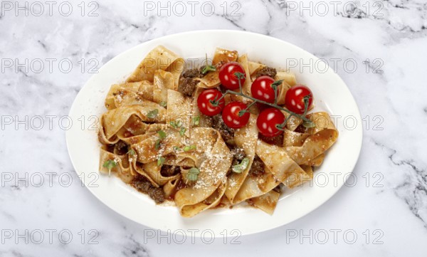 Pappardelle pasta with bolognese sauce, topped with parmesan cheese and cherry branch, homemade, no people