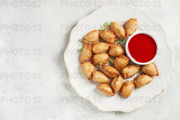 Fried mini chebureks, with sauce, on a decorative plate, hard light, no people