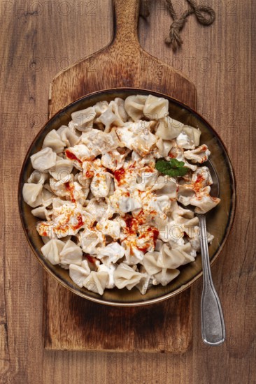 The dish features a generous serving of Turkish dumplings topped with velvety yogurt and a drizzle of spicy red sauce