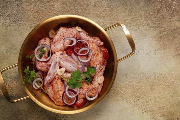 Chicken wings, in a brass saucepan, ready for cooking, grilling or baking, in a home kitchen, no people