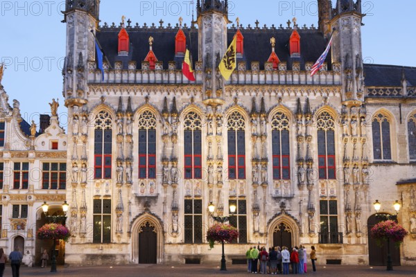 Tourist group looking at illuminated historic town hall of Bruges on Castle Square in the evening light, Stadhuis, Bruges, UNESCO World Heritage Site, Flanders, Belgium
