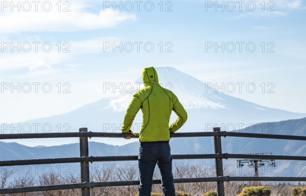 Tourist enjoying the view of the snow-covered summit of Mount Fuji volcano in spring, Owakudani, Hakone, Japan