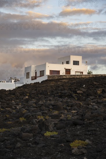 Typical white houses in the town of La Santa, at sunset, black volcanic rocks, Lanzarote, Canary Islands, Spain