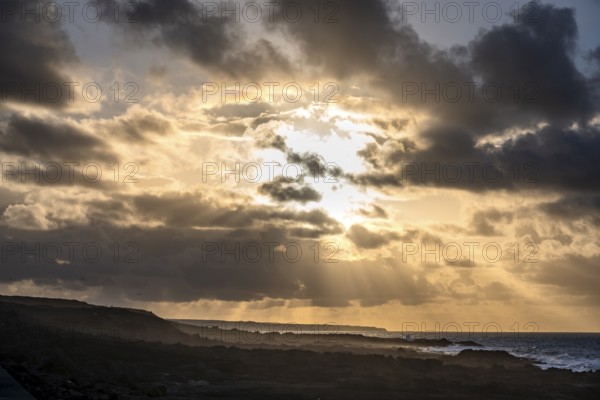 Dramatic cloudy sky with sunbeams at sunset, volcanic coast, La Santa, Lanzarote, Canary Islands, Spain