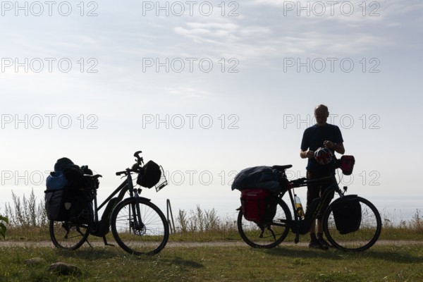 Two e-bikes with luggage bags, cyclist taking a break, back light, Ystad, Sweden