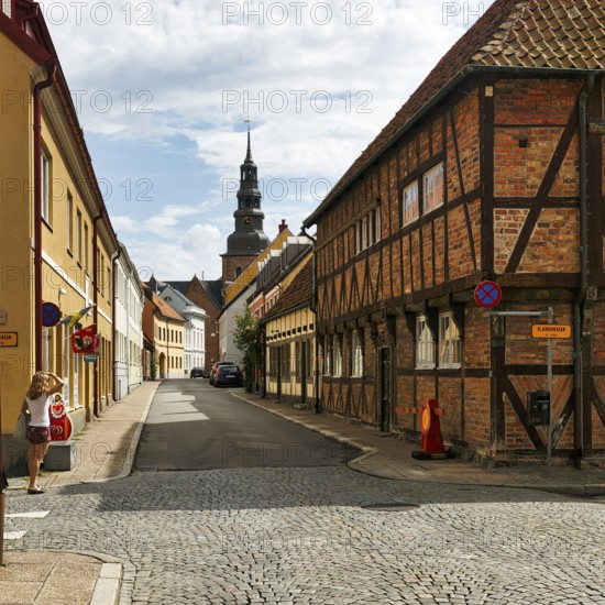 Charming cobblestone street, traditional half-timbered houses and brick buildings, St. Mary's Church tower, stroller, old town of Ystad, Sweden