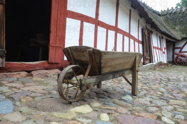 Old-fashioned wheelbarrow on paving stones and at half-timbered house in Den gamle by, The old village, open air museum in Odense, Fyn island, Fuen, Denmark, Scandinavia