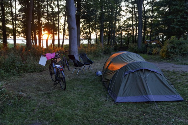 Tunnel tent, e-bike, cookware, two camping chairs on a campground at Lake Ringsjön, sunset, Horby, Skane, Skåne, Sweden