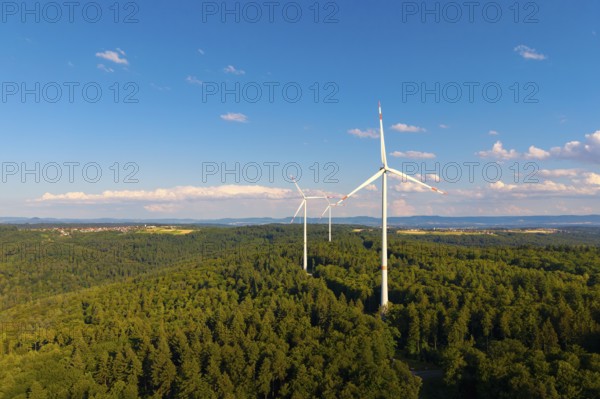 Green forests with several wind power plants under vivid blue sky with clouds, near Schorndorf, Rems-Murr-Kreis, Baden-Württemberg, Germany